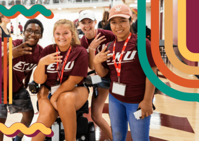 Students at the Rec Center, including a student who uses a wheel chair, posing for a photo at an event and showing EKU pride