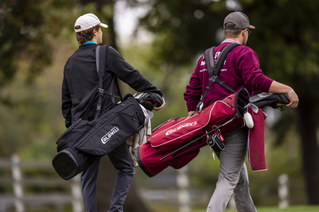 two golfers walking with EKU golf bags