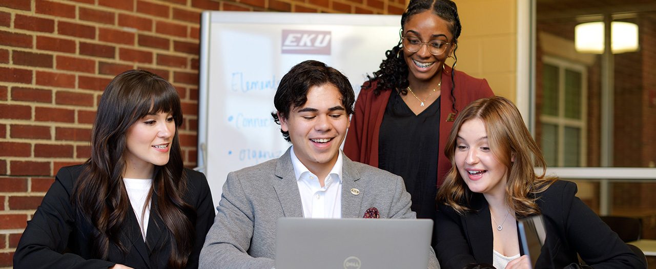 students pose holding their folders, notebooks, and laptops