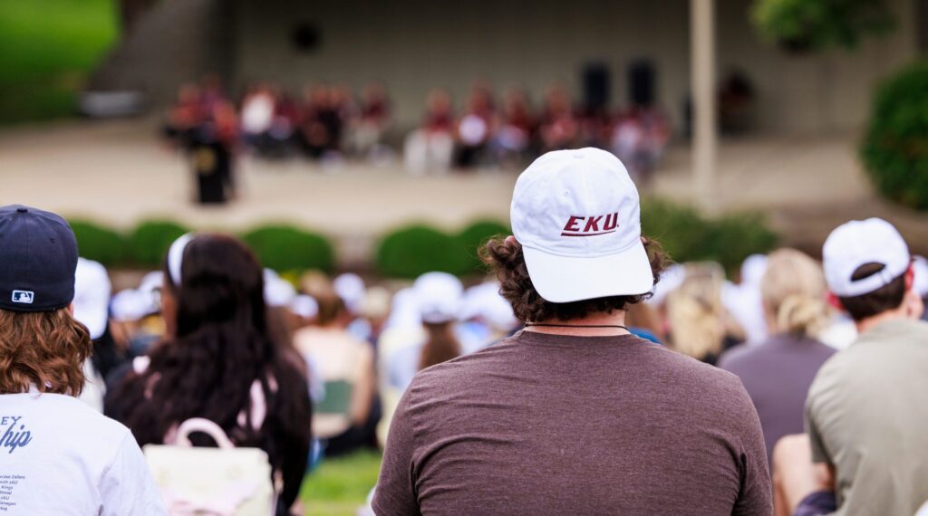 a student wears a white EKU ball cap backward