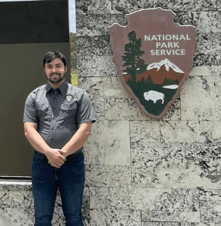 Photo of Kyle Januska, an EKU Alumnus standing in front of a National Park Service sign