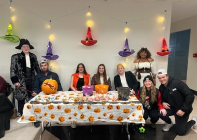 students wearing costumes pose at a table decorated for Halloween