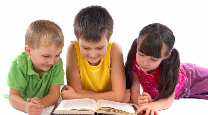 Three children reading a book.
