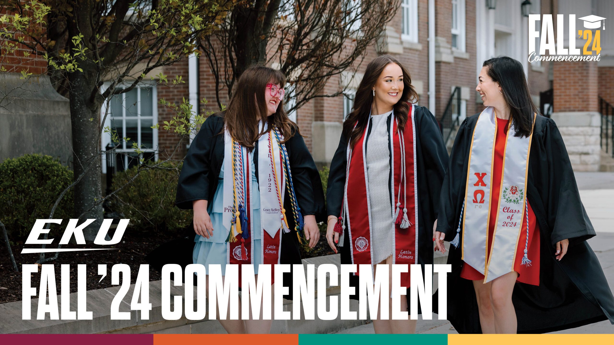 three students wearing commencement gowns walk together