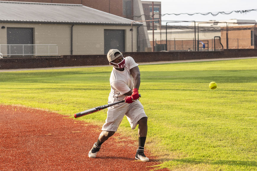One student swinging baseball bat at softball on Combs Baseball field