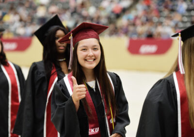 a smiling student gives a thumbs up during the commencement ceremony