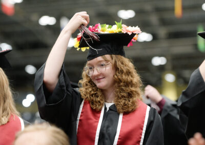 a student moves the tassel on her flowered mortar board