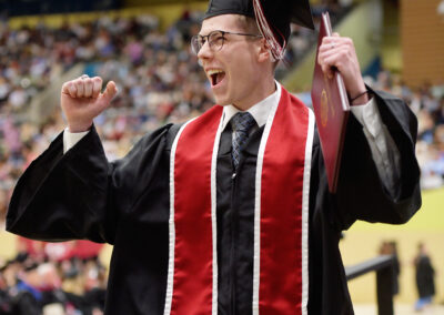 a student raises their hands in celebration during the commencement ceremony