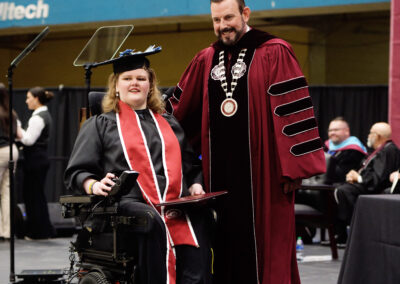 a student in a wheelchair poses with President McFaddin during the commencement ceremony