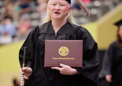 a student poses with their diploma cover during commencement