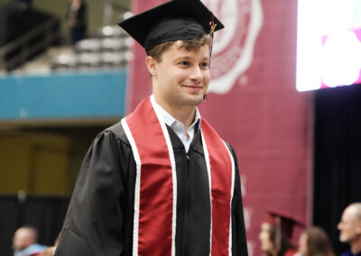a smiling student walking in cap and gown