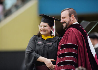 President McFaddin shakes hands with a student as he awards their diploma