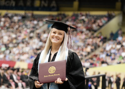 a smiling student poses with their diploma cover