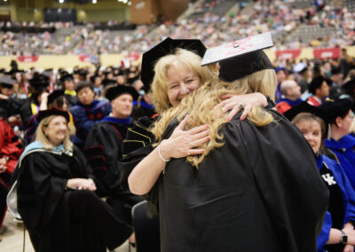 a faculty member hugs a student during the commence ceremony