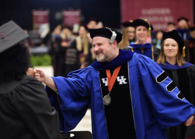 a faculty member fist bumps another person during the commencement ceremony