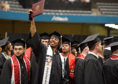 a student holds up their diploma cover during the commencement ceremony