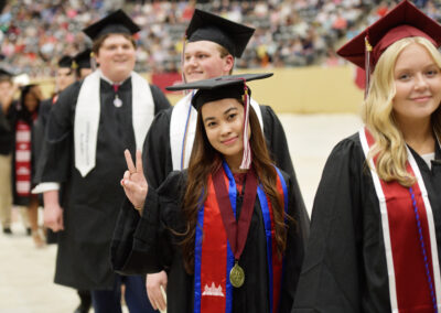 a student makes a V with their fingers during the commencement ceremony procession