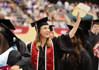 a smiling student waves during the commencement ceremony procession
