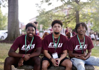 three students pose on a bench outside