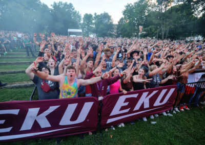 Large crowd of EKU students celebrate with arms raised on the front row of the Flo Rida outdoor concert