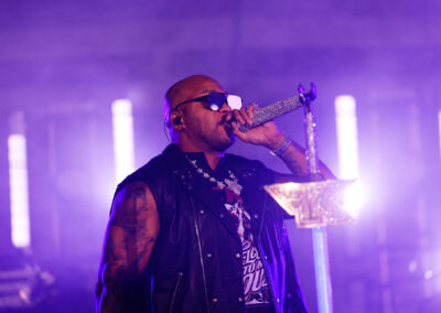 Flo Rida, with purple lighting behind him, addresses the crowd of EKU students while holding a rhinestoned microphone