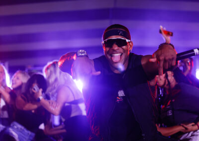 While female EKU students dance behind him on stage, a rapper poses with tongue out and microphone in hand in the dark at Flo Rida concert