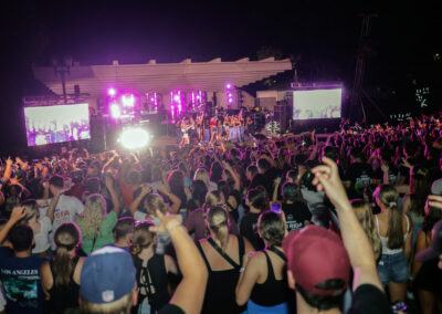 A view of the stage from the back of the crowd as students celebrate on stage at night with Flo Rida