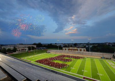 fireworks go off as students form a Big E on the football field