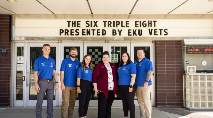 Six members of Omega Delta Sigma standing in front of a sign that reads "The Six Triple Eight Presented by EKU Vets" at Eastern Kentucky University.