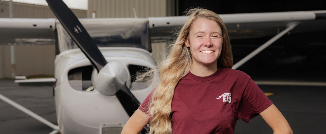 Smiling female Aviation student stands in front of a Cessna 172 single-engine airplane at EKU's aviation facility the Central Kentucky Regional Airport