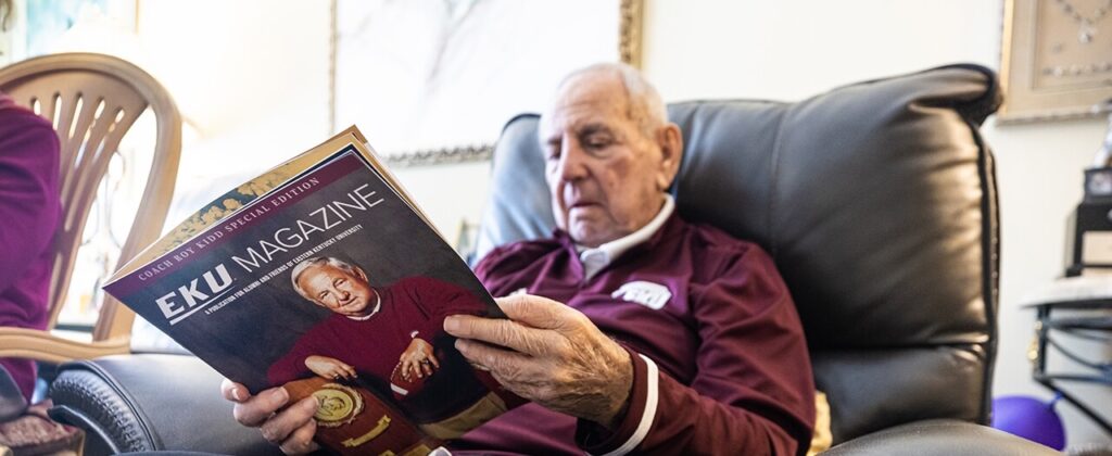 Famed EKU football coach Roy Kidd relaxes in his recliner and reads a copy of EKU Magazine with his photo on the cover.