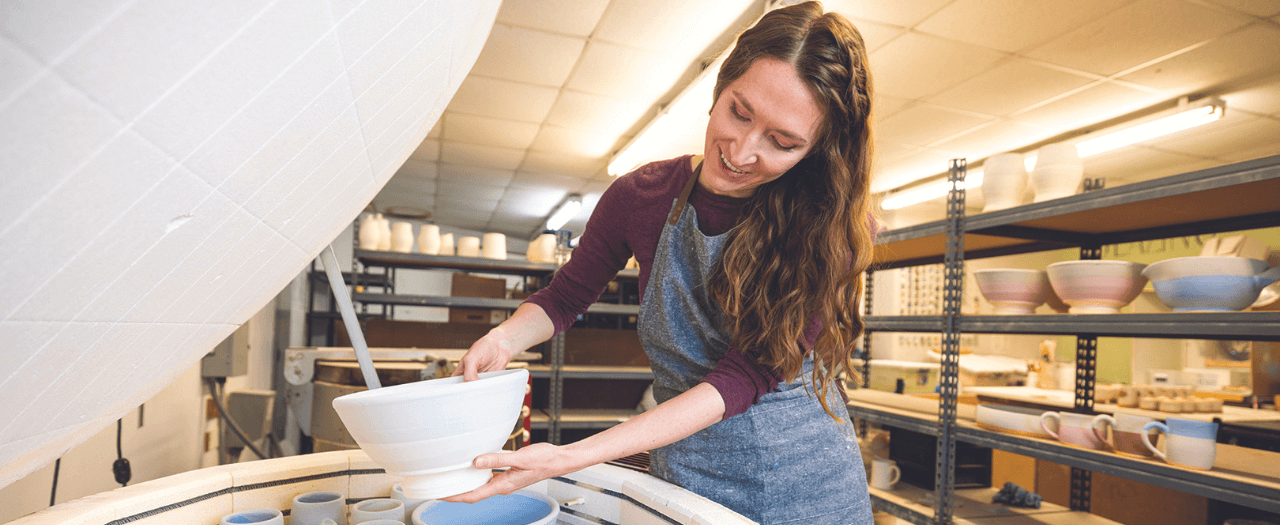 EKU student and creator of Dirty South Pottery places a bowl into the kiln in studio.