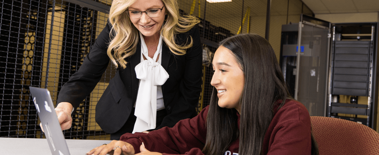 EKU Evans Banking and Financial Services Director Maggie Abney points out something on a laptop screen to a female EKU student in a sever room.