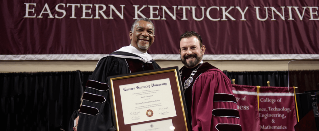 Dr. Aaron Thompson smiles with EKU president David McFaddin and his honorary doctorate degree at the commencement ceremony.