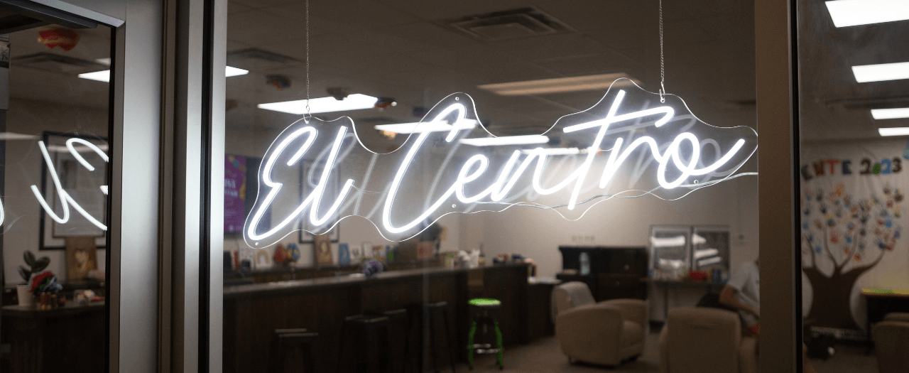 A white neon sign saying "El Centro" hangs on the window of a new space on EKU's campus.