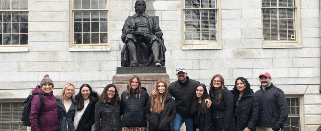 Group of EKU students pose in front of statue at Harvard University