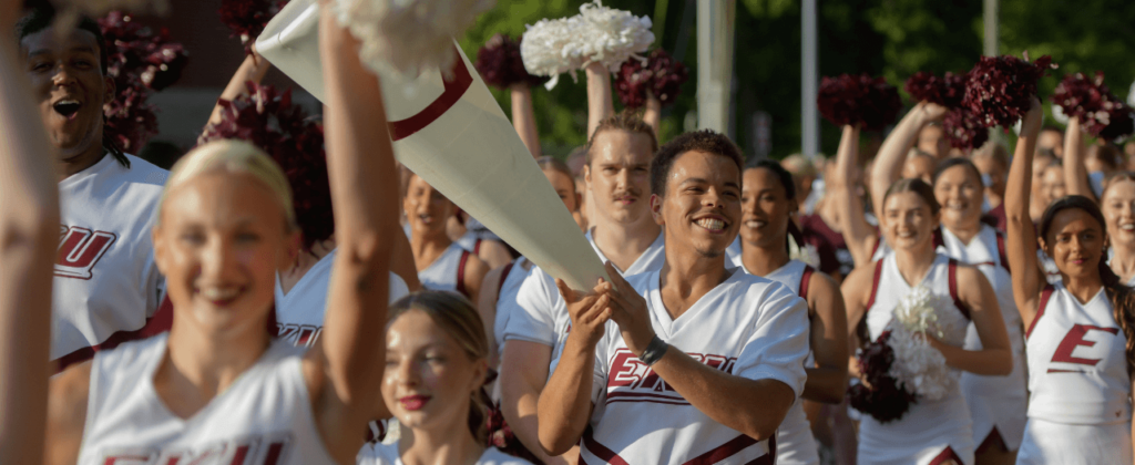 A parade of male and female EKU cheerleaders celebrate with pom poms and megaphones at Big E Welcome.