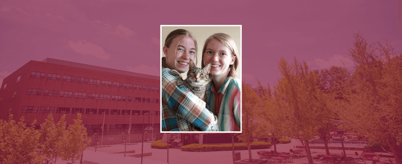 EKU student Rosalie Richburg and sister, Amy, snuggle together while Rosalie holds a tabby cat.