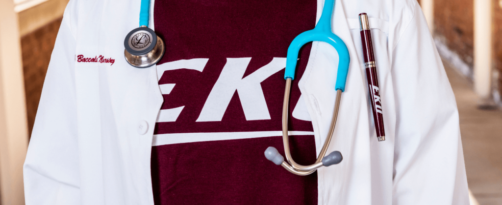 An extreme close up of a white nursing jacket and with EKU t-shirt under and a stethoscope