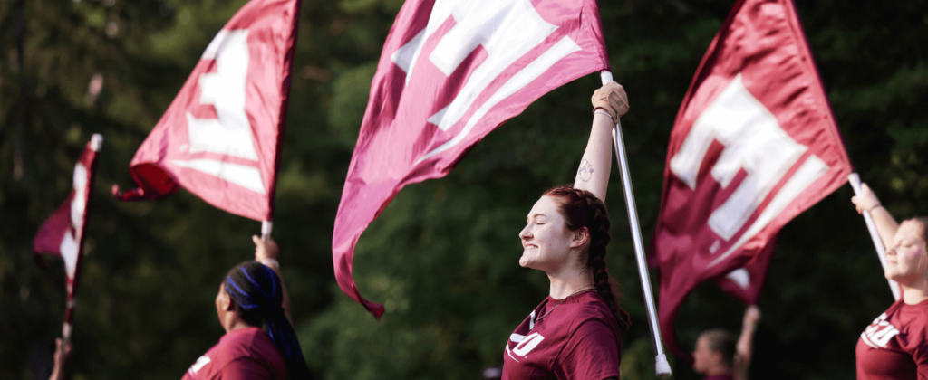 EKU color guard team marches and performs with giant EKU flags at 2024's Big E Welcome walk.