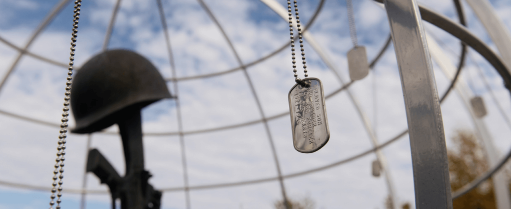 A close up view of dog tags hang from the metal globe encompassing the Veterans Memorial on EKU's campus.