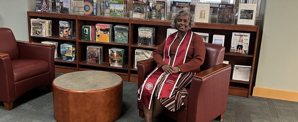 EKU graduate Dian Gentry relaxes in a chair wearing her EKU Latin Honors sash.