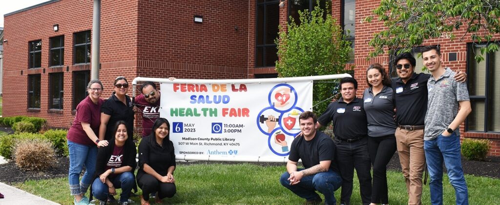 A group of EKU bilingual students with the event poster outside the Madison County Public library