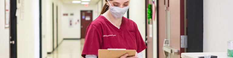 Female EKU nursing student with mask and clipboard.