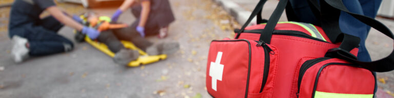 a person carries a paramedicine bag toward responders kneeling by a patient outside