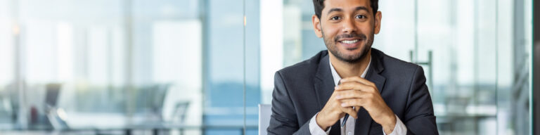 a professionally dressed man sits in a law office and smiles at the camera