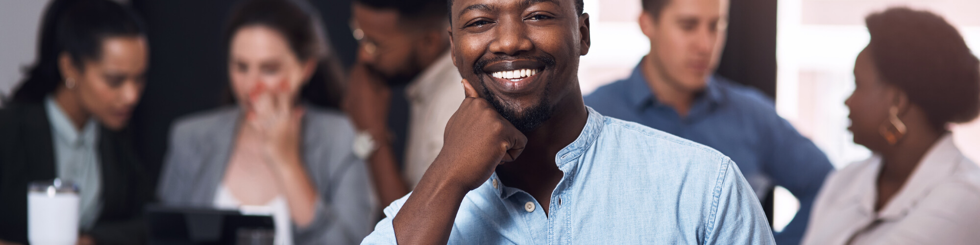 Smiling male educator in a group with other educators in the background.