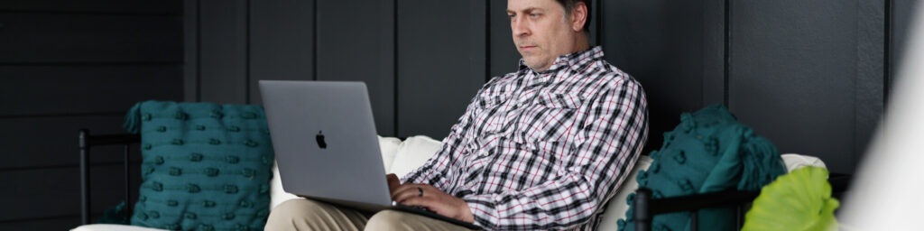 A professional man relaxes outside with his laptop after work to do his coursework.