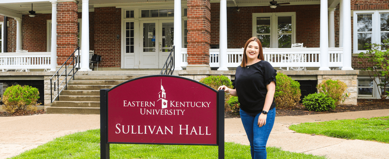 EKU student Torrey White stands beside the Sullivan Hall sign in front of the dorm.