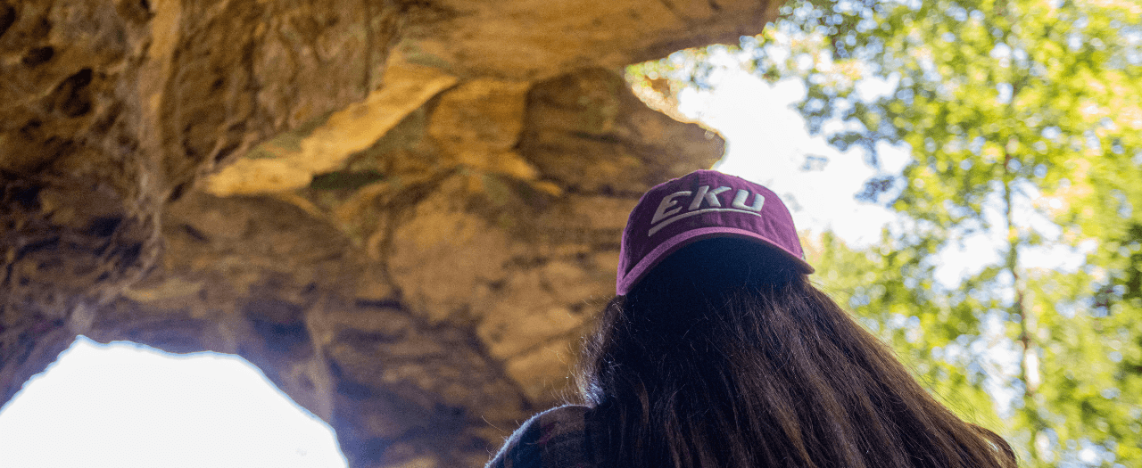 Student wearing EKU hat backwards hikes at Red River Gorge.